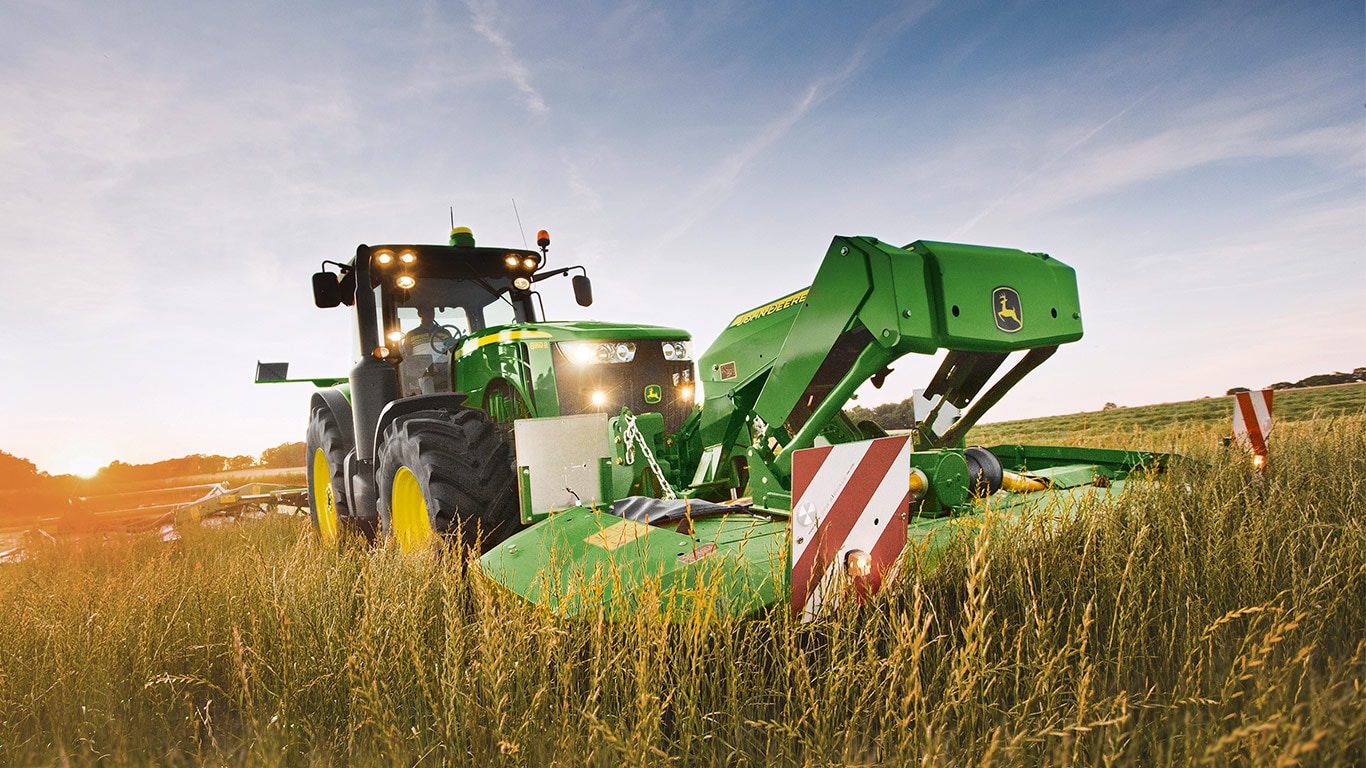En John Deere-traktor høster en hveteåker